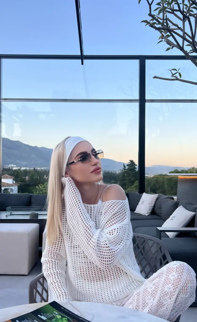Alisa in white crochet knit on a terrace at sunset